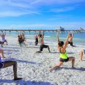 Un groupe de personne en plein cours de yoga sur la plage