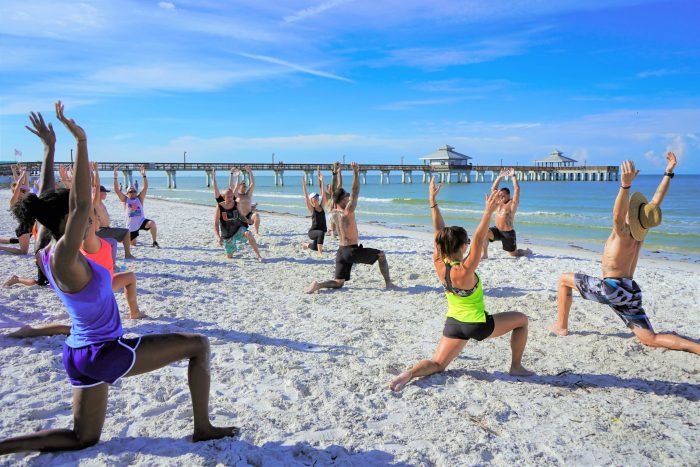 Un groupe de personne en plein cours de yoga sur la plage