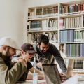 3 collègues installés devant un ordinateur dans une bibliothèque