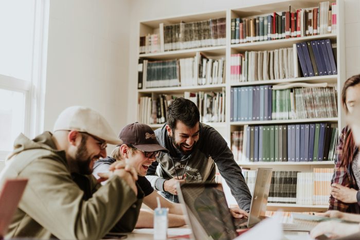 3 collègues installés devant un ordinateur dans une bibliothèque