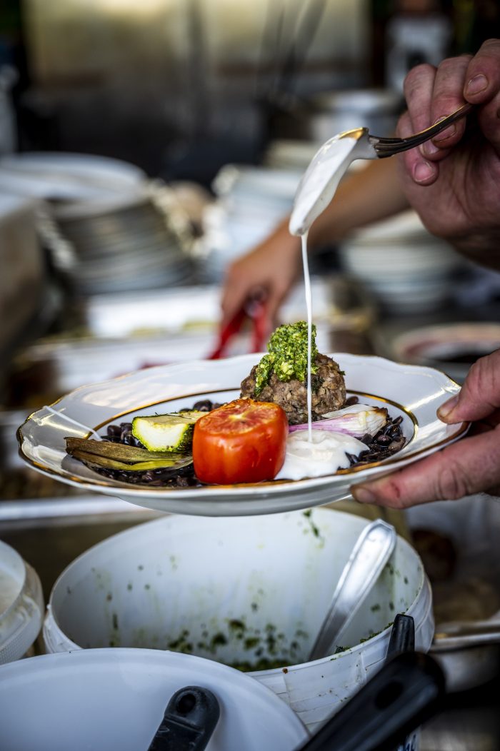 Une personne en train d'assaisonner un plat dans une assiette avec du Gwell